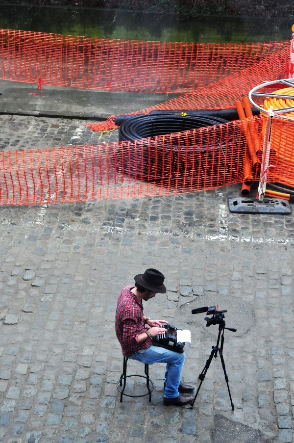 Na środku ulicy (Cadixstraat), która właśnie z powodu remontu była wyłączona z ruchu, siedział młody mężczyzna i pisał.